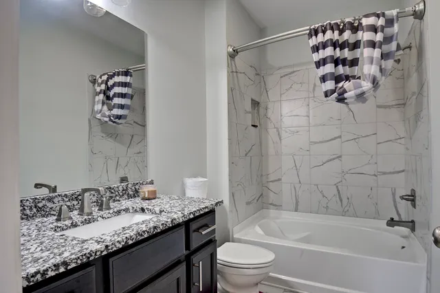 a bathroom with a granite countertop sink a toilet and bathtub