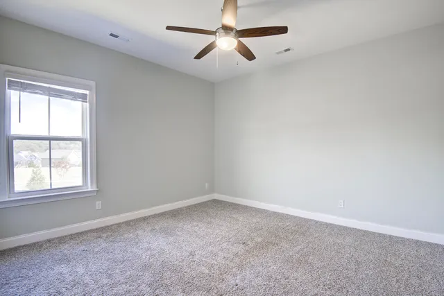 an empty room with a window and a fan