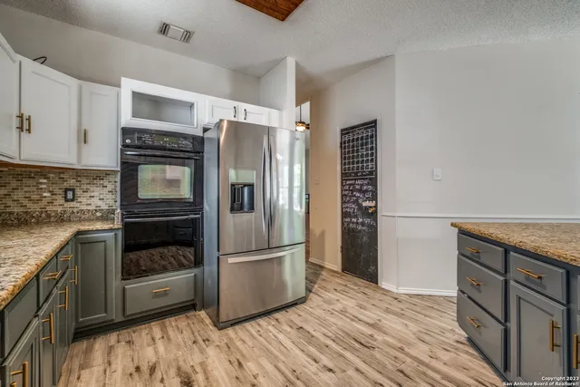 a kitchen with granite countertop a refrigerator and a stove top oven