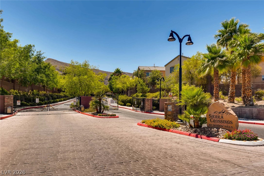 10451 Processor Court Las Vegas, NV 89129 - Photo 28 of 28 Secure community entrance with an inviting paved drive, lush landscaping, and majestic mountain views.
