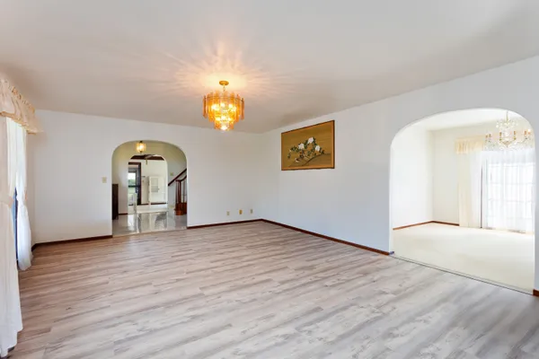 a view of an empty room with window and wooden floor