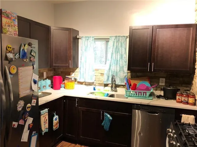 a kitchen with stainless steel appliances a sink dishwasher and cabinets with wooden floor