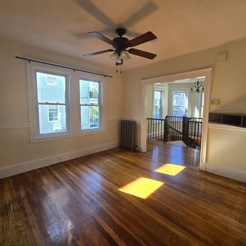 a view of an empty room with window and wooden floor