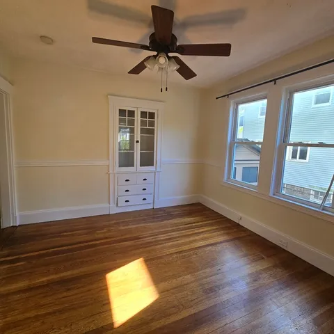a view of an empty room with a window and wooden floor