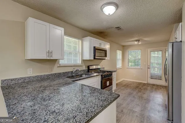 a kitchen with stainless steel appliances granite countertop a stove a refrigerator and a microwave