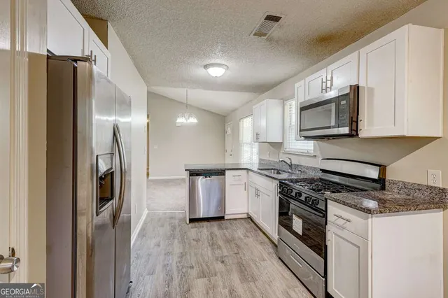 a kitchen with stainless steel appliances granite countertop a refrigerator and a stove top oven