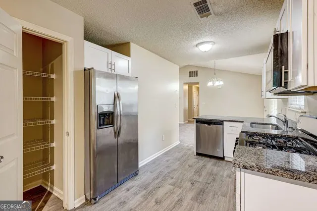 a kitchen with stainless steel appliances granite countertop a refrigerator a stove and a sink