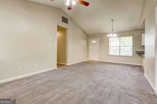 en empty room with windows and chandelier fan