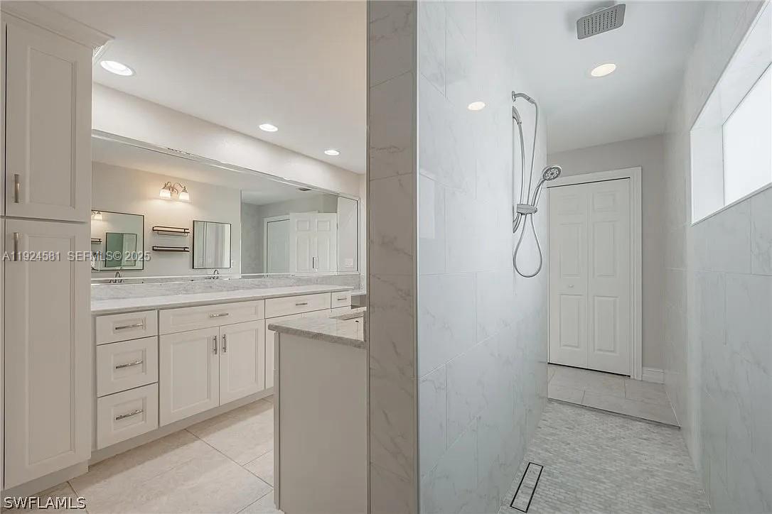 830 Angelo Avenue Lehigh Acres, FL 33971 - Photo 18 of 29 a bathroom with a double vanity sink a mirror and a shower
