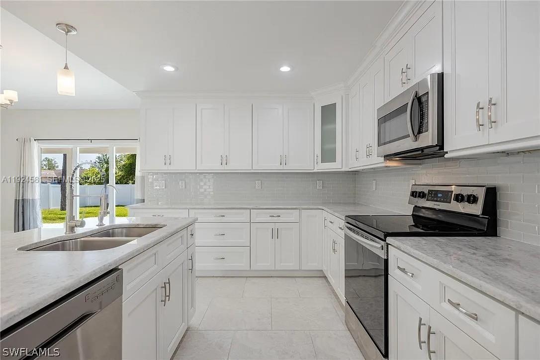 830 Angelo Avenue Lehigh Acres, FL 33971 - Photo 3 of 29 a kitchen with stainless steel appliances granite countertop a sink and a stove