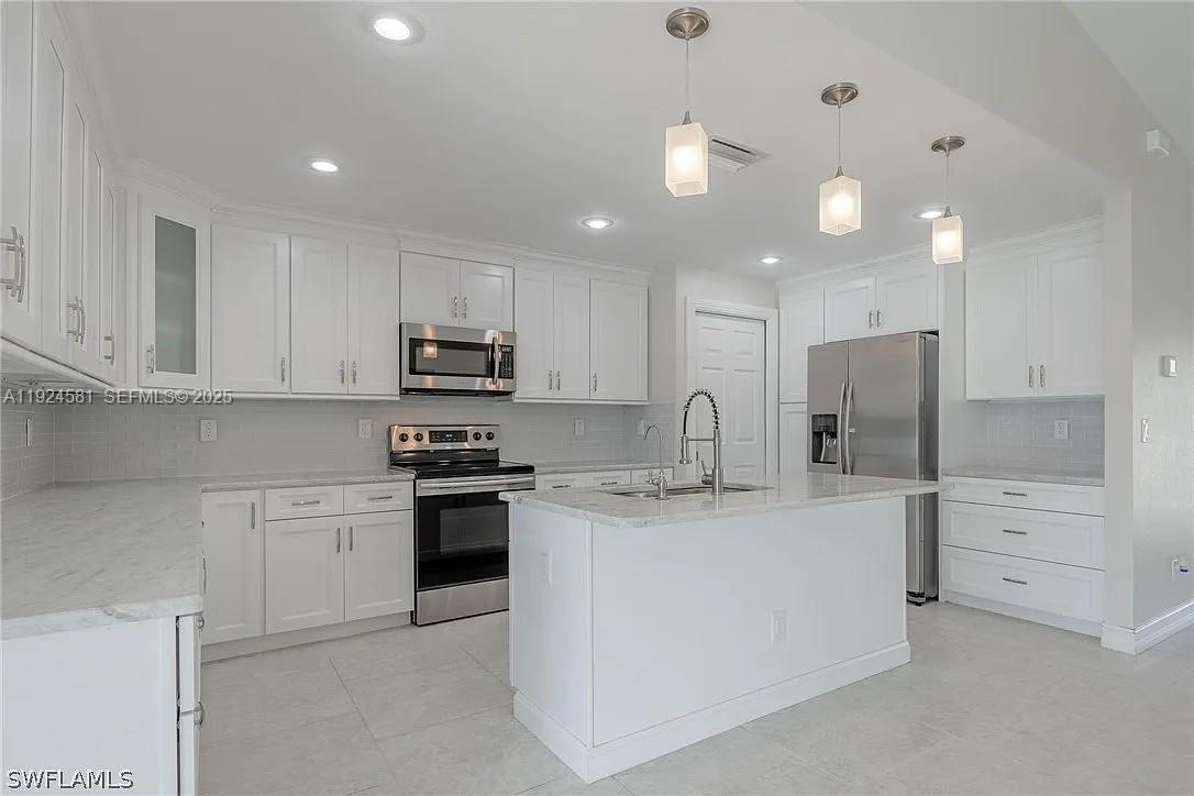 830 Angelo Avenue Lehigh Acres, FL 33971 - Photo 4 of 29 a kitchen with stainless steel appliances granite countertop a sink and a stove