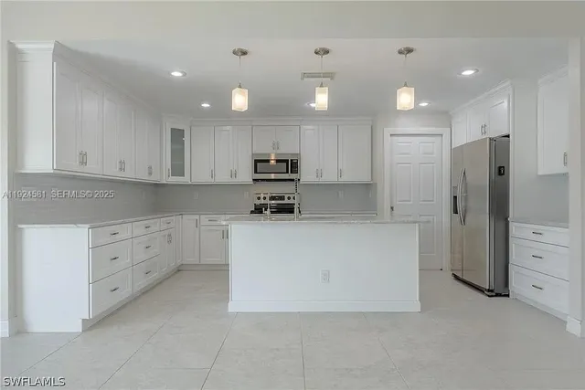 a large white kitchen with cabinets