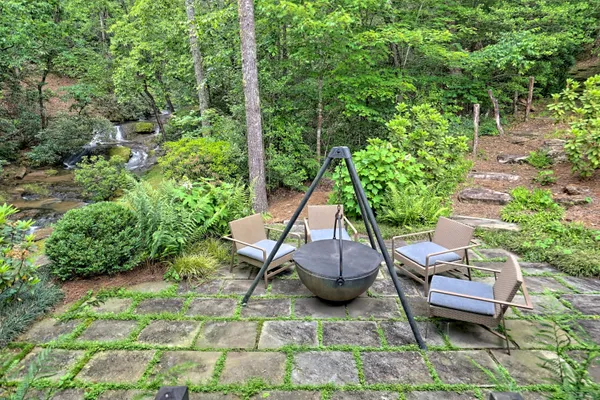 a view of a backyard with lawn chairs plants and large tree