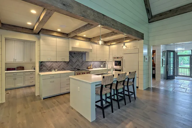 a kitchen with stainless steel appliances granite countertop a stove top oven a sink dishwasher and wooden cabinets with wooden floor