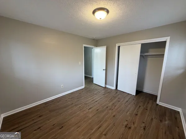 an empty room with wooden floor & closet area
