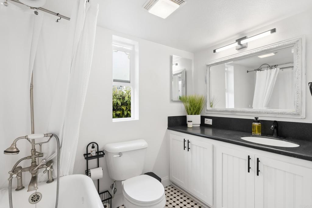 1624 North Coast Highway 101, Unit 2 Encinitas, CA 92024 - Photo 13 of 43 a bathroom with a granite countertop sink a toilet and mirror