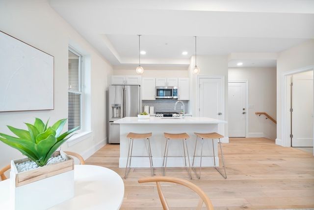 a view of kitchen with stainless steel appliances granite countertop a refrigerator a sink a stove and a dining table