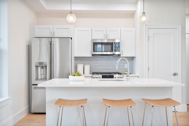 a kitchen with stainless steel appliances granite countertop a sink a stove a refrigerator a center island and cabinets