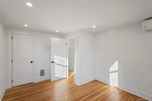 a view of empty room with wooden floor and kitchen