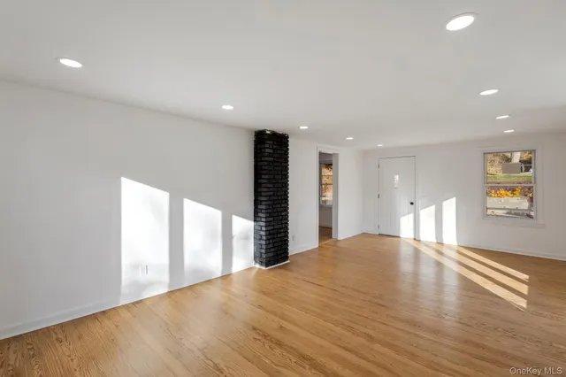 a view of an empty room with window and wooden floor
