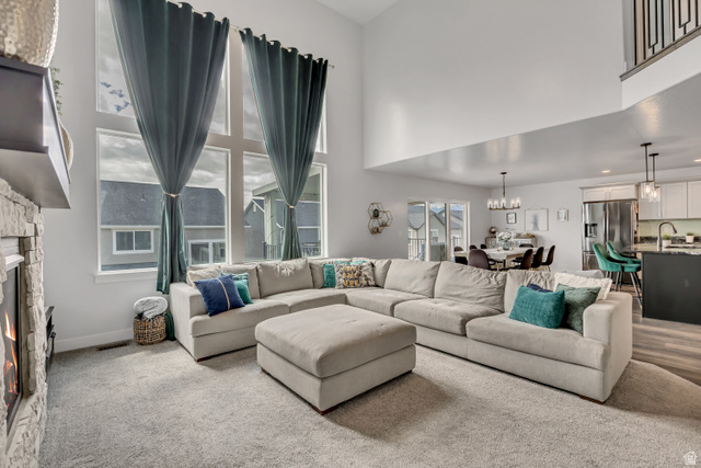 1577 Quailhill Road Saratoga Springs, UT 84045 - Photo 7 of 46 Carpeted living room with a fireplace, a high ceiling, and suspended lighting