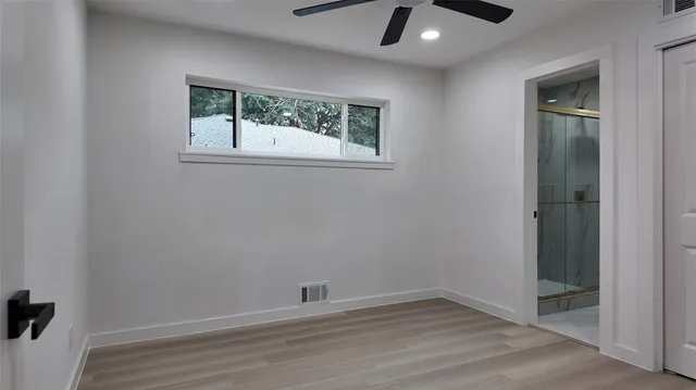 an empty room with a window and a ceiling fan