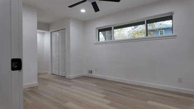 an empty room with a windows and ceiling fan