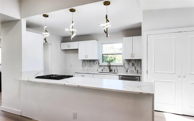 a kitchen with granite countertop a sink a counter space appliances and cabinets