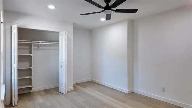 an empty room with a hallway and a ceiling fan