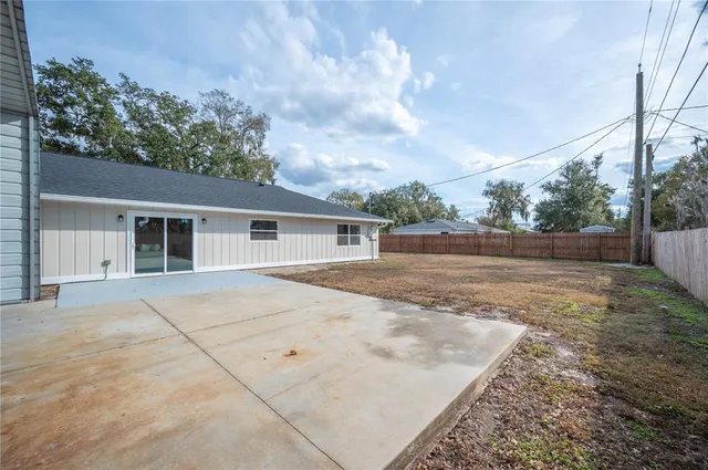 a view of a backyard with wooden fence and a large tree