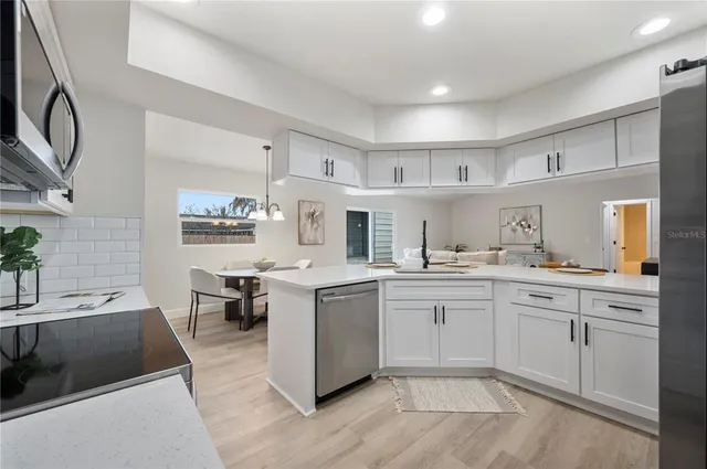a large white kitchen with cabinets a sink and appliances