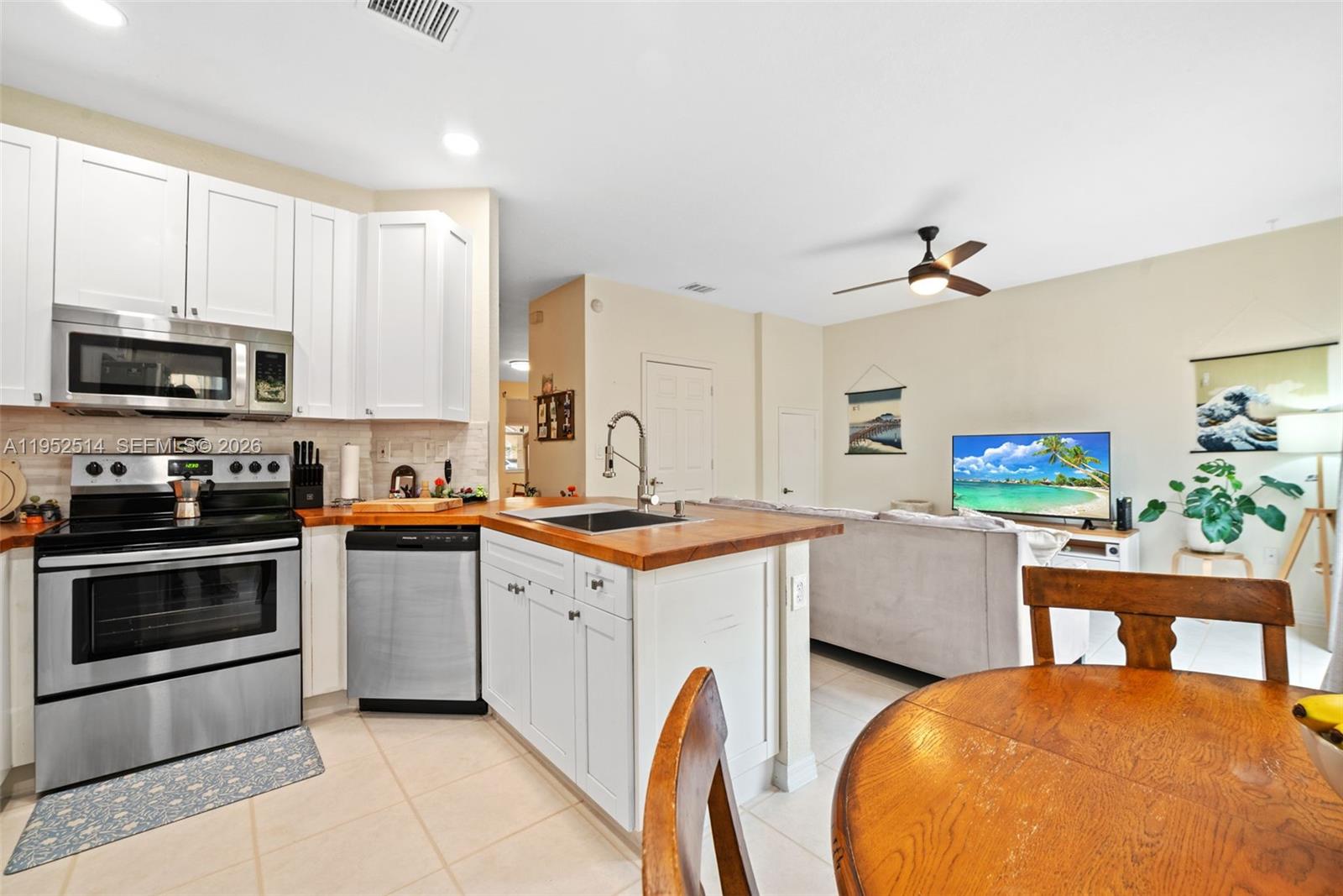 16634 Southwest 79th Terrace Miami, FL 33193 - Photo 11 of 25 a kitchen with stainless steel appliances a stove a sink cabinets and a dining table