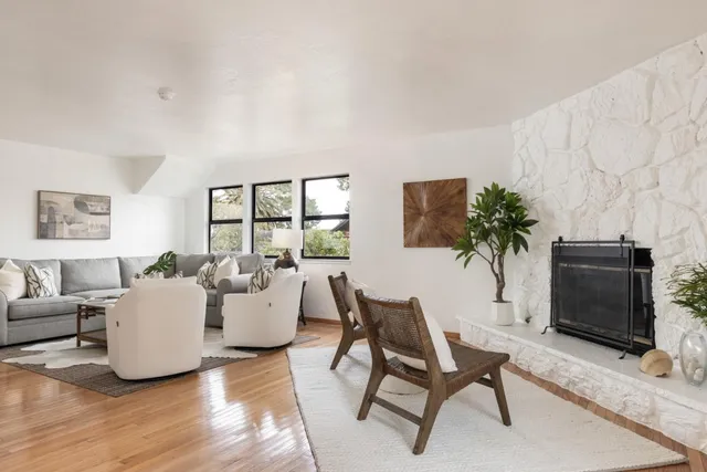 a living room with furniture a potted plant and a wooden floor