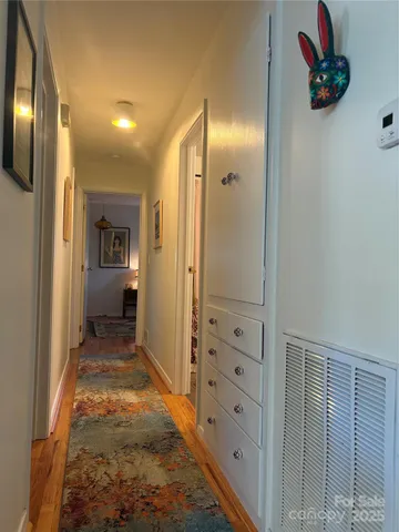 a view of a hallway with a cabinet and a bathroom