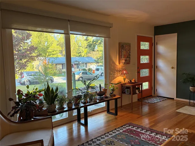 a living room with furniture hard wood floor and a floor to ceiling window