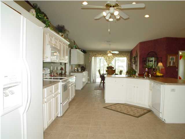 2549 Crescent Road Navarre, FL 32566 - Photo 12 of 22 a large white kitchen with kitchen island a large counter space a sink stainless steel appliances and cabinets