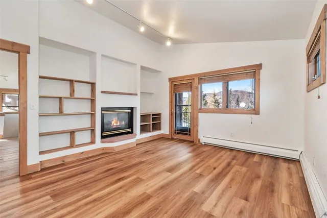 a view of empty room with wooden floor and fireplace