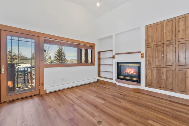 a view of an empty room with wooden floor fireplace and a window