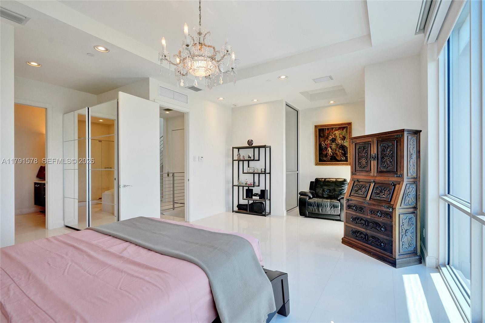 2725 Northeast 1st Street Pompano Beach, FL 33062 - Photo 35 of 59 a bedroom with a bed a dresser and a chandelier