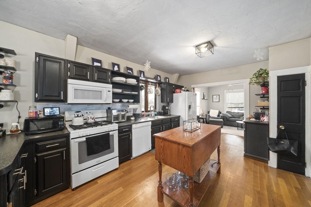 73 Monroe Street Abington, MA 02351 - Photo 8 of 28 a kitchen with stainless steel appliances granite countertop a stove top oven a sink dishwasher a dining table and chairs with wooden floor