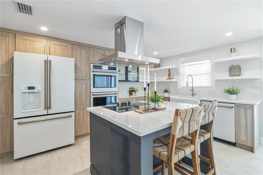 405 28th Street Holmes Beach, FL 34217 - Photo 18 of 50 a kitchen with stainless steel appliances a refrigerator a stove a sink and white cabinets with wooden floor