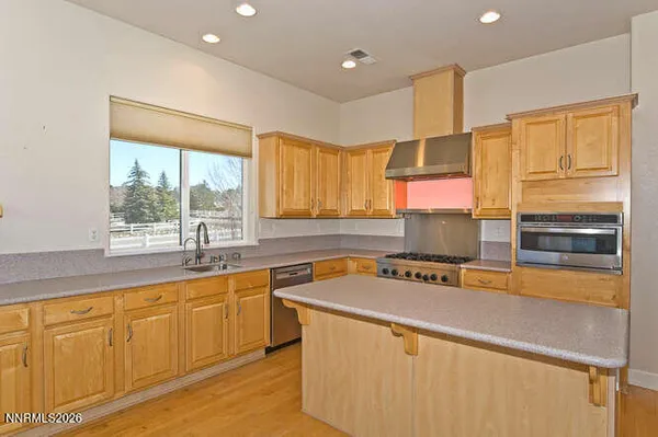a kitchen with stainless steel appliances granite countertop a sink dishwasher and a fireplace with wooden floor