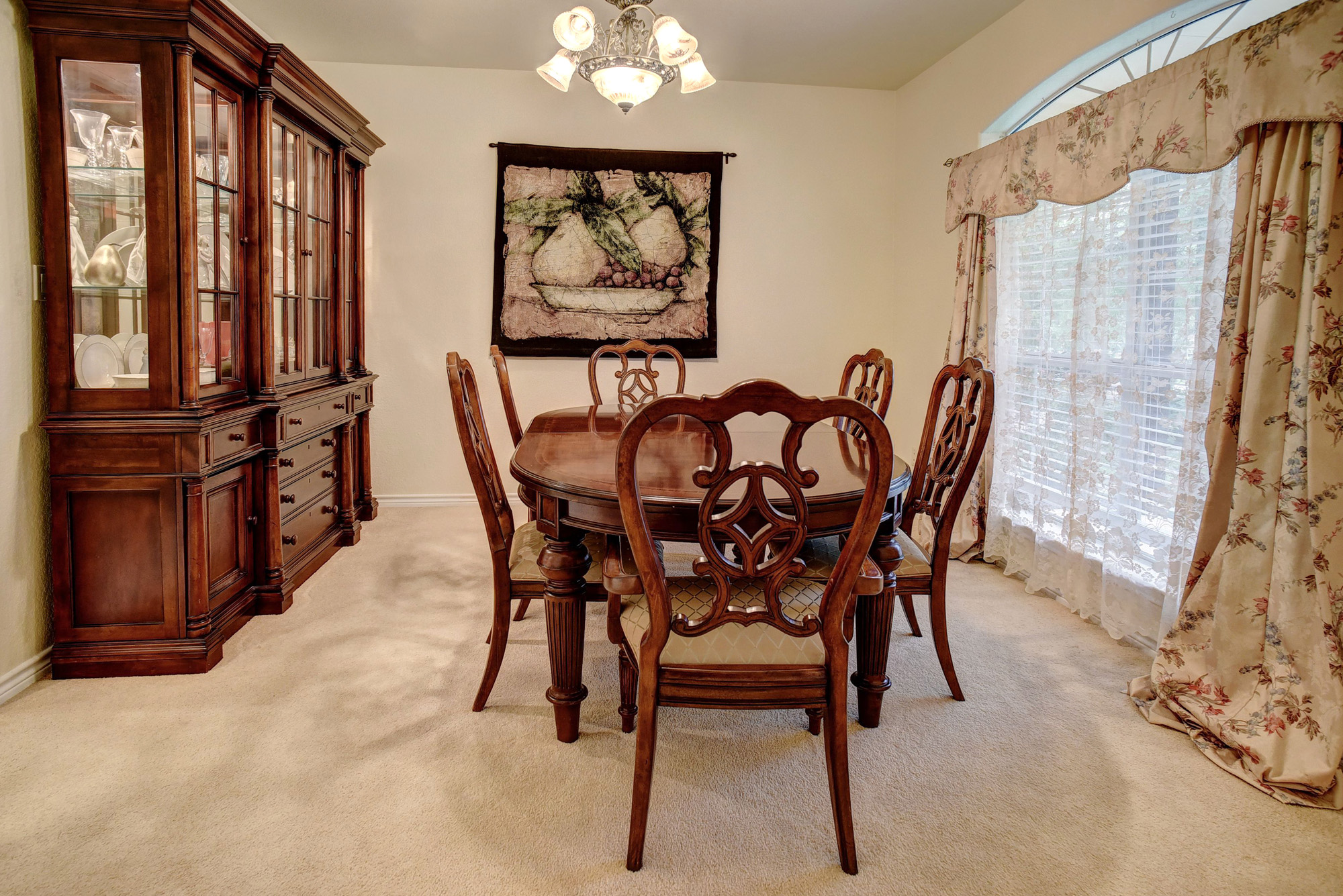 147 Spring Meadow Road Bastrop, TX 78602 - Photo 12 of 40 Carpeted dining area featuring an arched window with floral drapery, a ceiling-mounted light fixture, and light-toned walls