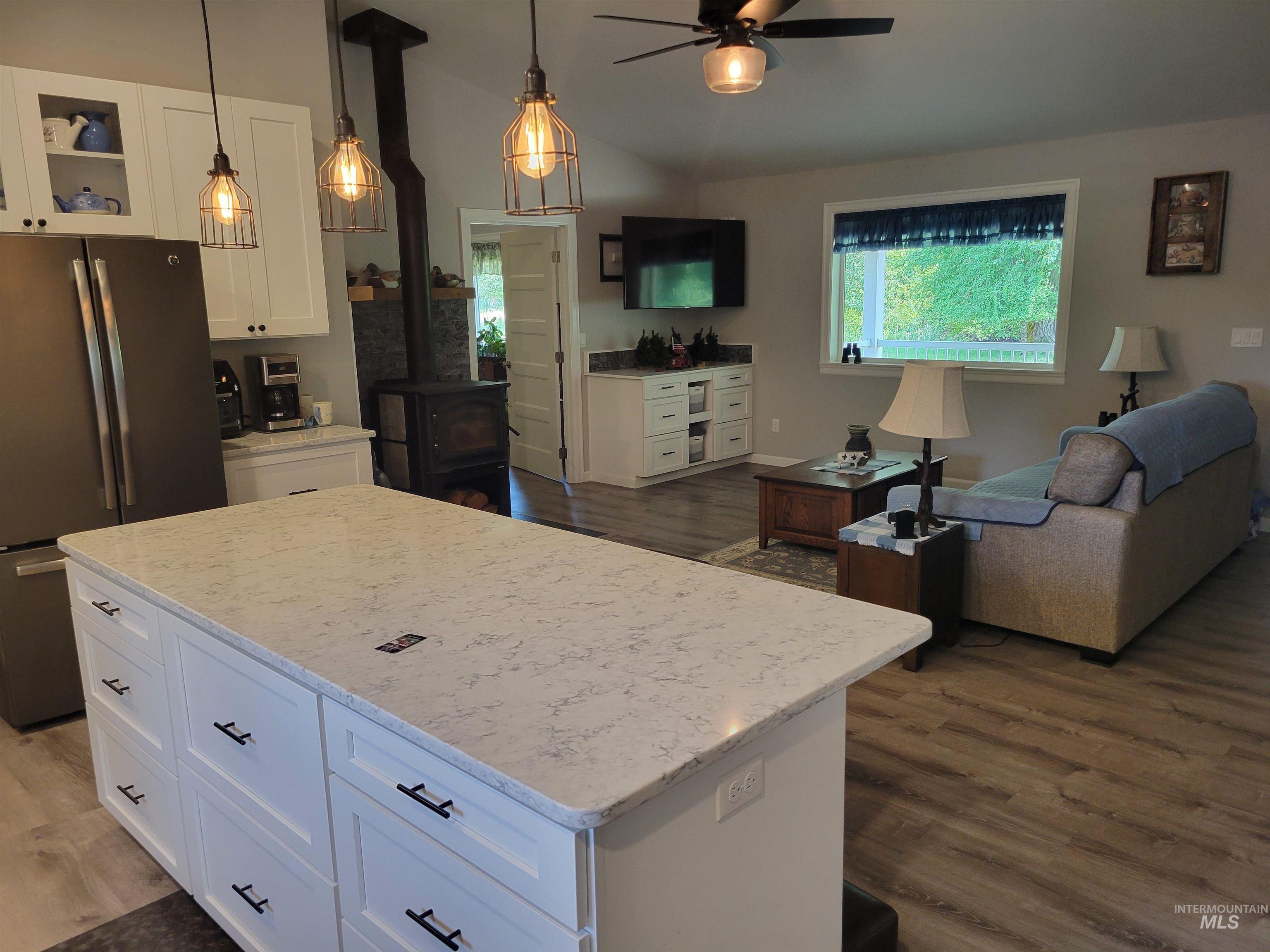437 Clearcreek Road Kooskia, ID 83539 - Photo 13 of 45 Kitchen featuring freestanding refrigerator, a wood stove, a ceiling fan, white cabinets, and wood finished floors