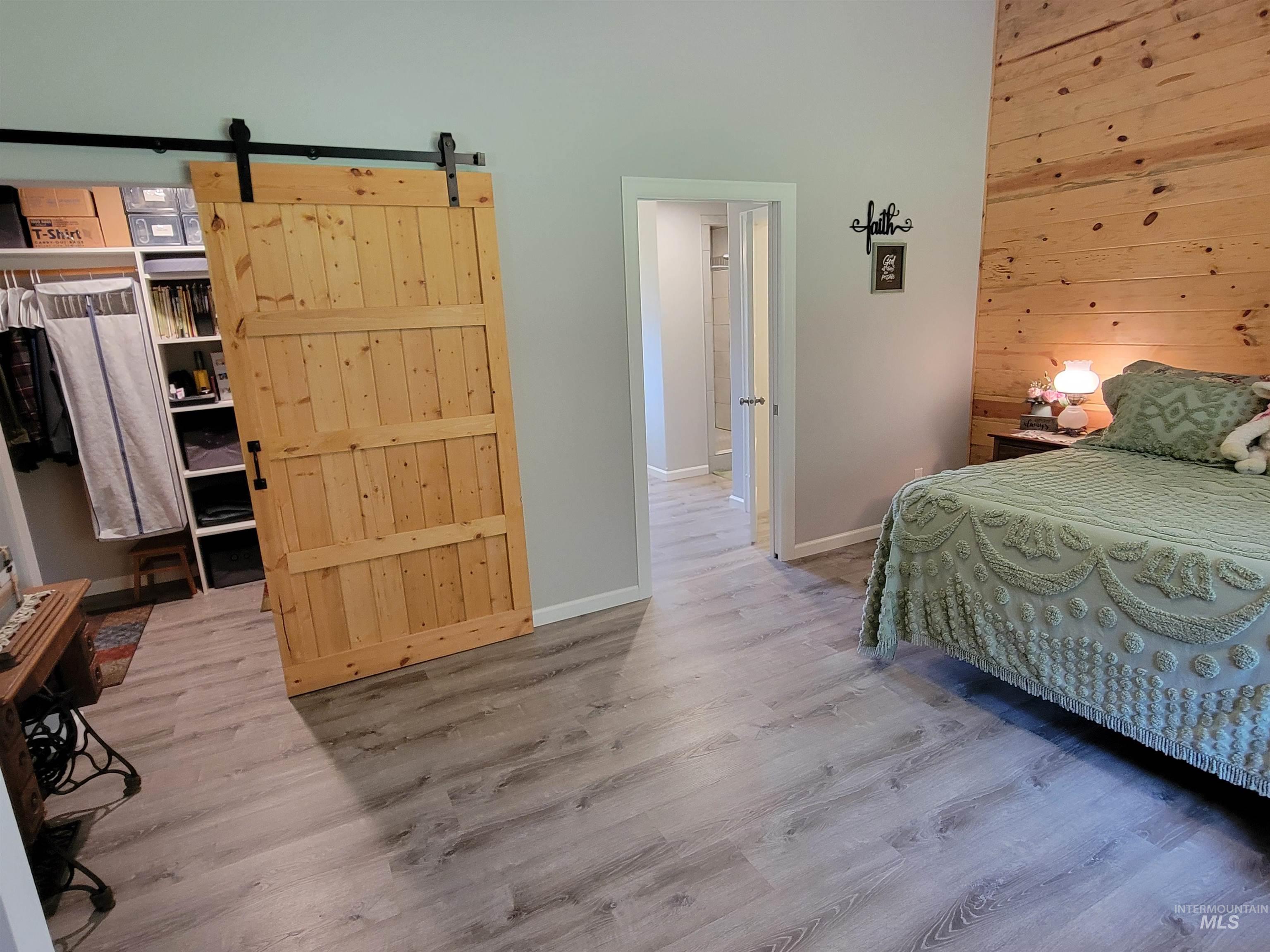 437 Clearcreek Road Kooskia, ID 83539 - Photo 18 of 45 Bedroom featuring wood finished floors, wood walls, a barn door, and a high ceiling