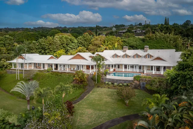a view of a big house with a big yard and large trees