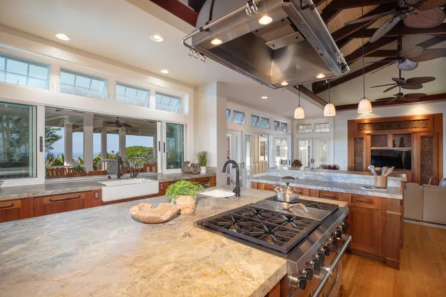 a kitchen with stainless steel appliances granite countertop a stove a sink dishwasher and a dining table with wooden floor