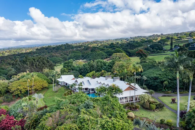 a view of a white building with a swimming pool and lawn chairs