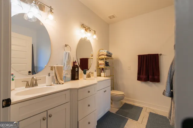a bathroom with a double vanity sink toilet and mirror