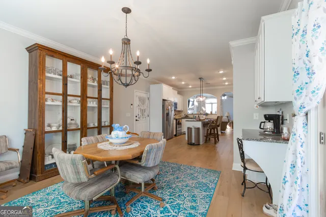 a dining room with wooden floor a chandelier a wooden table and chairs